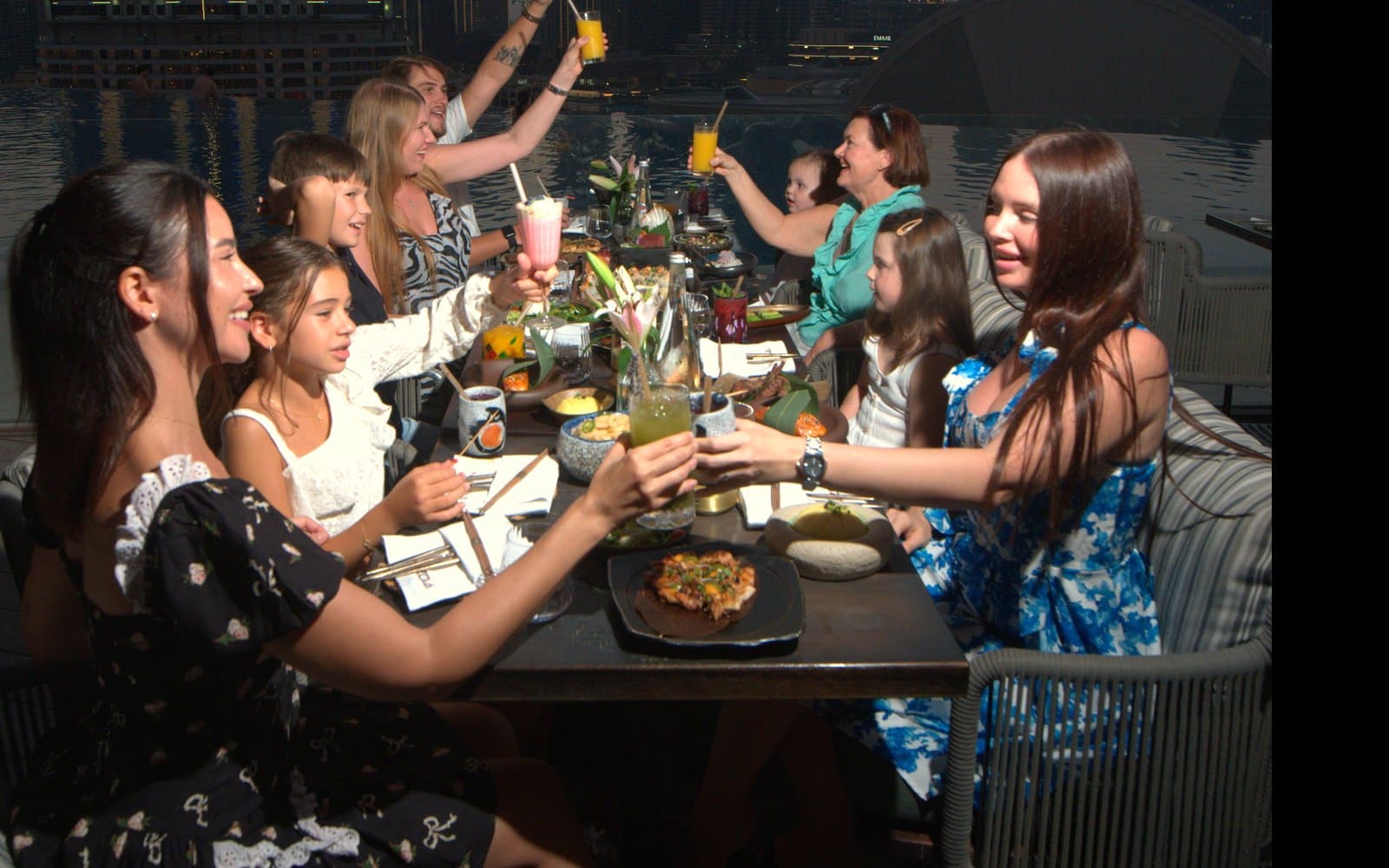 Families raising their glasses across a long table at Flamingo Brunch on the NAZCAA terrace